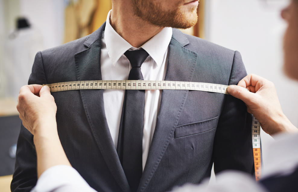 Close up of man in suit being measured by a tailor